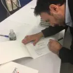 A man is signing a book at an event.