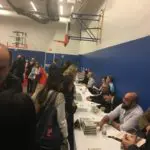 A group of people sitting at tables with books.