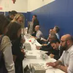 A group of people sitting at tables with books.