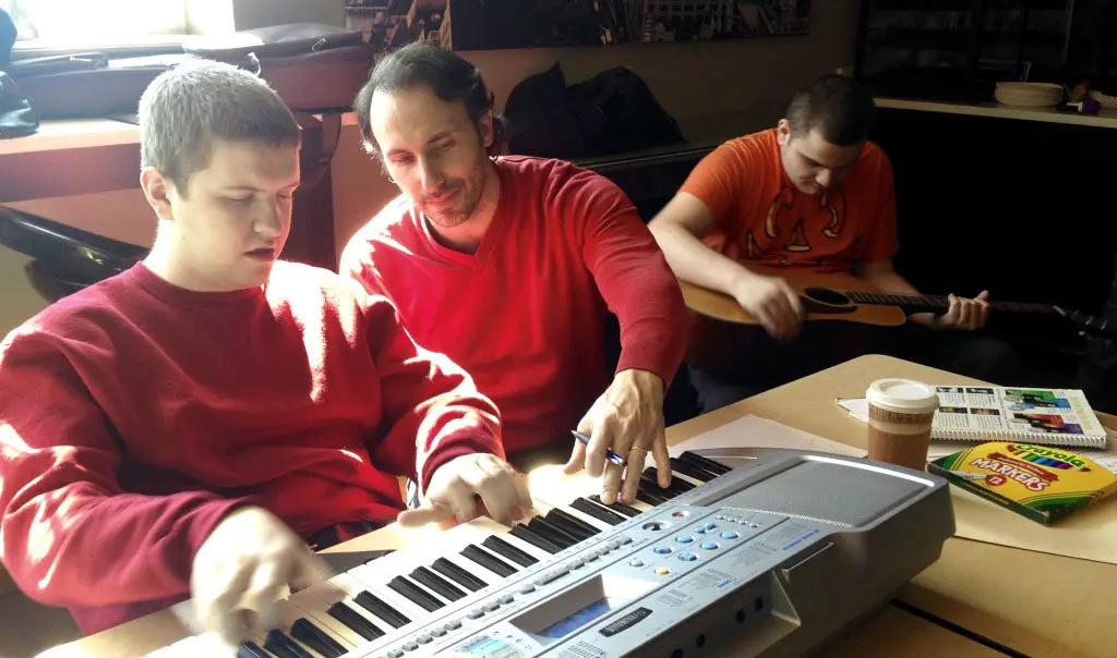 A man and two boys playing on an electronic keyboard.