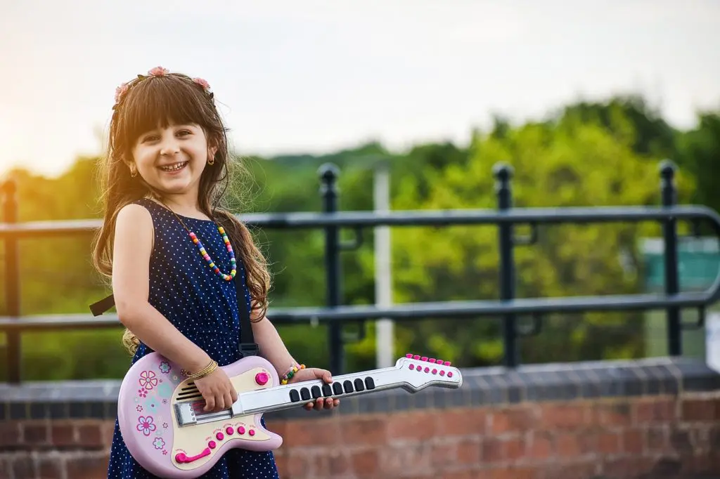 A little girl holding a toy guitar in her hands.