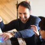 A man and boy playing piano together.
