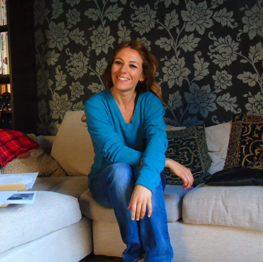 A woman sitting on the couch smiling for the camera.