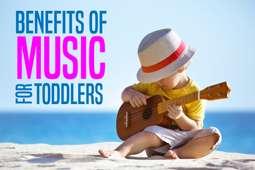 A child sitting on the beach playing a guitar