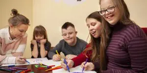 A group of children sitting at a table with pencils.