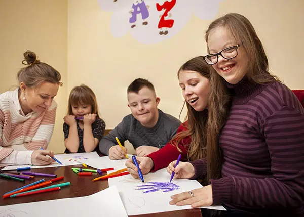 A group of children sitting at a table with pencils.