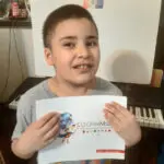 A boy holding up a sheet of paper.