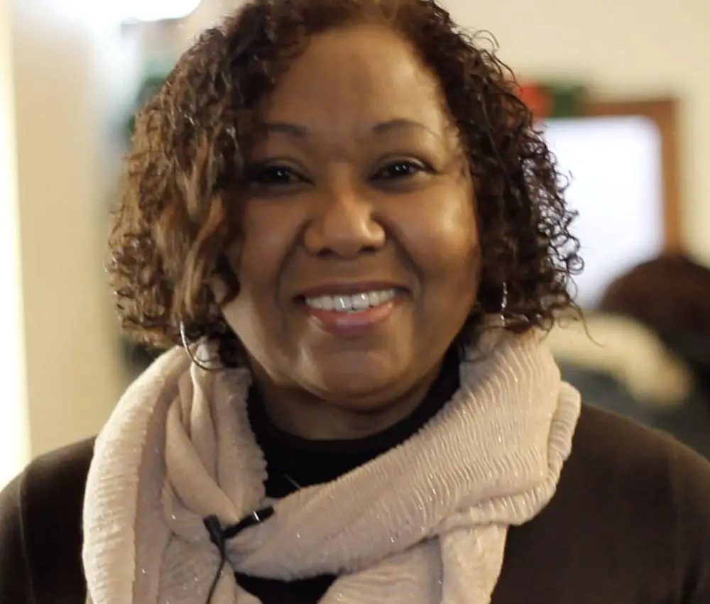 A woman with curly hair wearing a scarf.