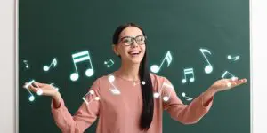 A woman standing in front of a chalkboard with musical notes.