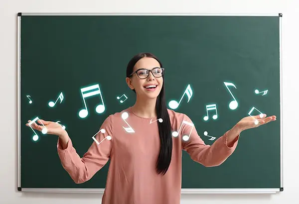 A woman standing in front of a chalkboard with musical notes.