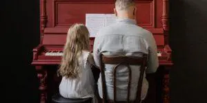 A man and girl sitting at the piano