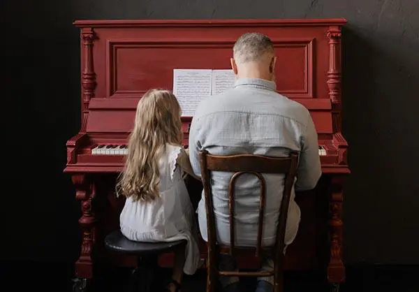 A man and girl sitting at the piano