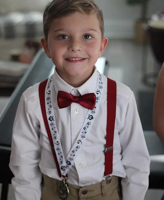 A young boy wearing suspenders and bow tie.