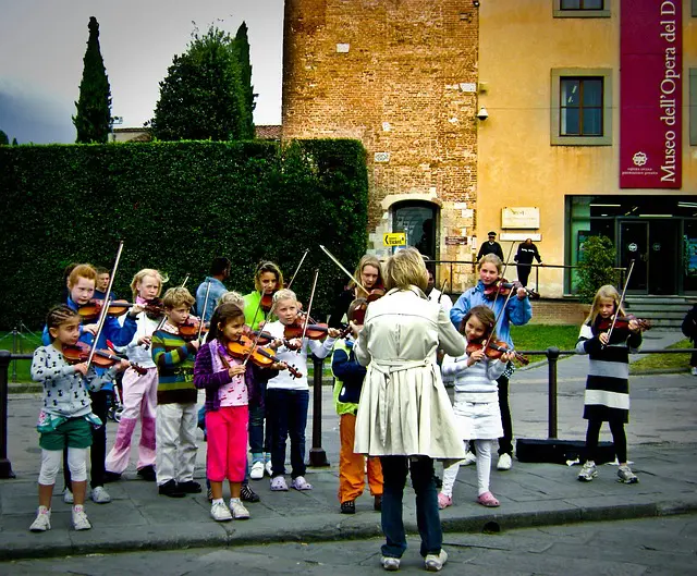 A group of children playing violin on the street.