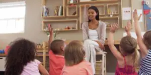 A woman sitting on the floor of a room with children.