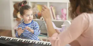 A woman and child playing with a toy piano.