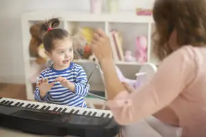 A woman and child playing with a toy piano.