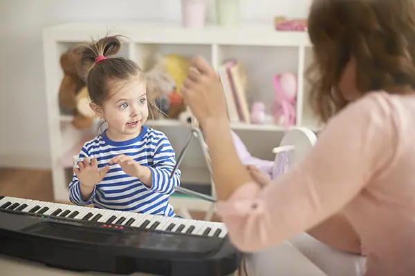 A woman and child playing with a toy piano.