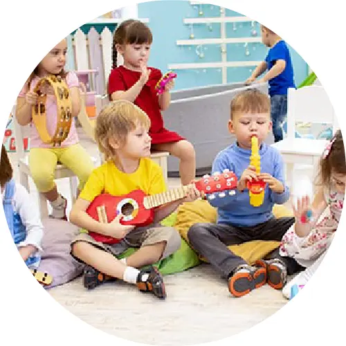 A group of children sitting on the floor playing instruments.