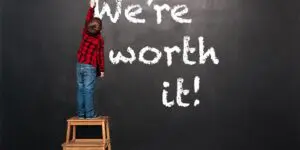 A person standing on top of a stool in front of a chalkboard.