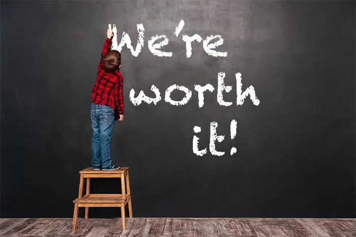 A person standing on top of a stool in front of a chalkboard.