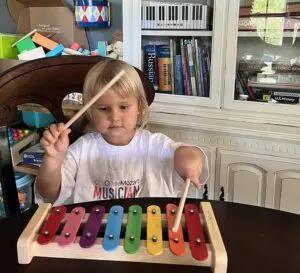 A little girl is playing with a toy xylophone.