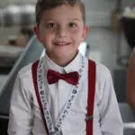 A young boy wearing red suspenders and bow tie.