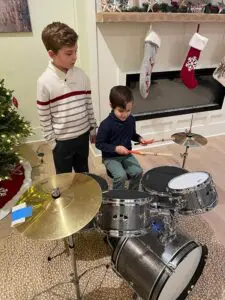 Two young boys playing drums in a living room.