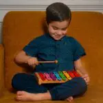 A young boy is playing with his xylophone.