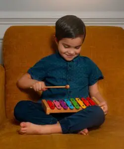 A young boy is playing with his xylophone.