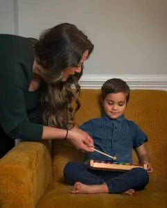 A woman and child are playing with a wooden toy.