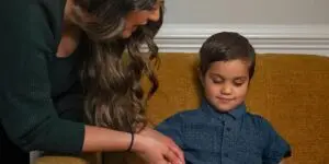 A woman and child are playing with a wooden toy.