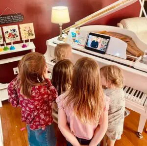 A group of children watching a video on the piano.