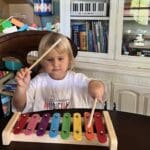 A little girl is playing with a toy xylophone.