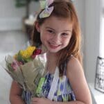 A little girl holding flowers in her hands.