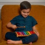 A young boy is playing with his xylophone.