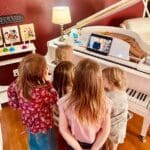 A group of children watching a video on the piano.